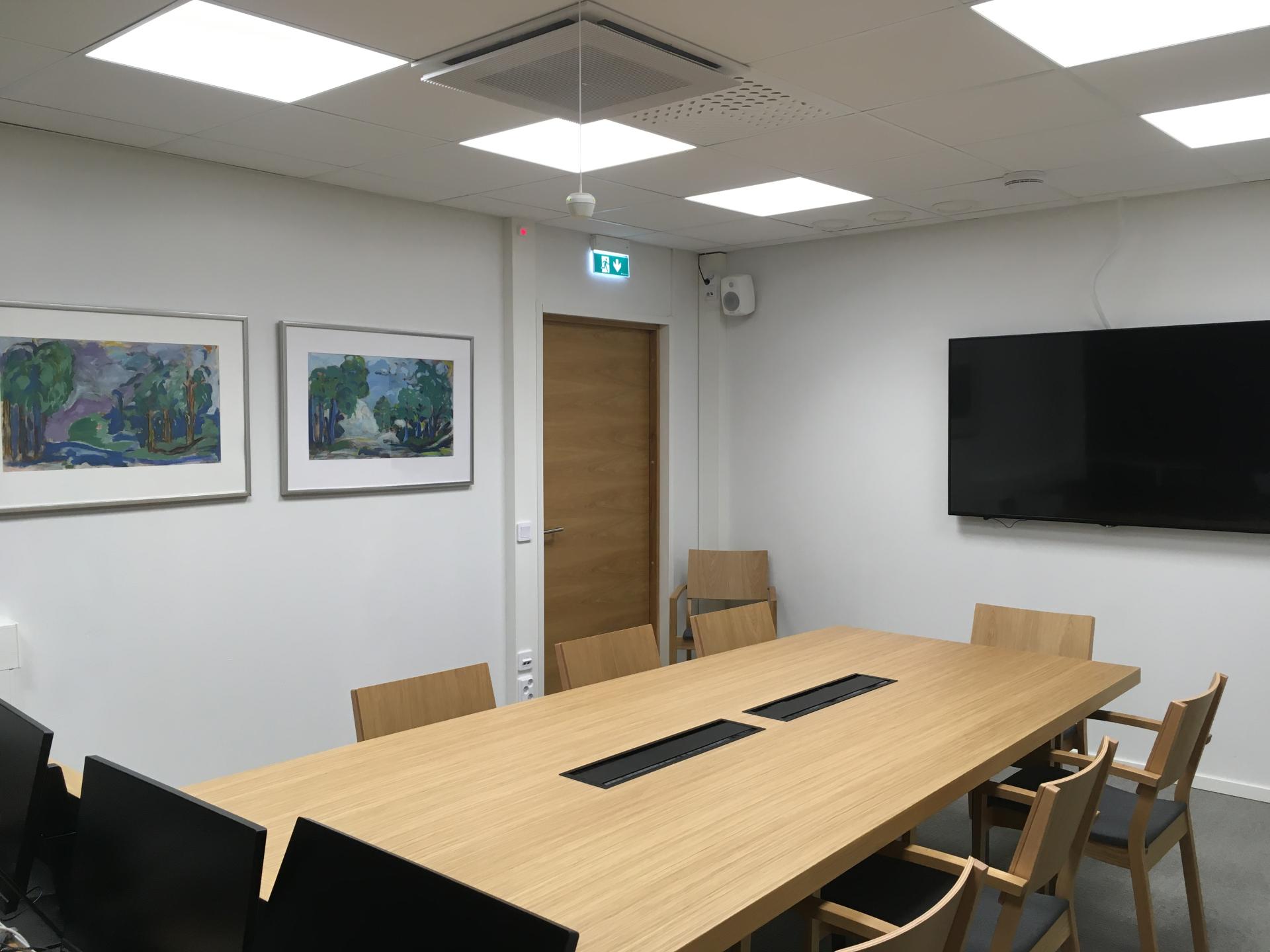 Kuvassa näkyy asianosaisten pöytä ja seinällä olea esitysnäyttö.